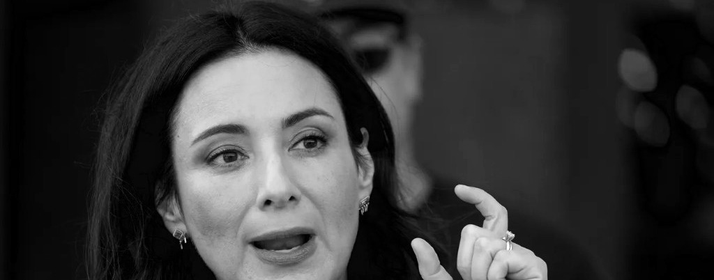Woman speaking and gesturing at a press conference